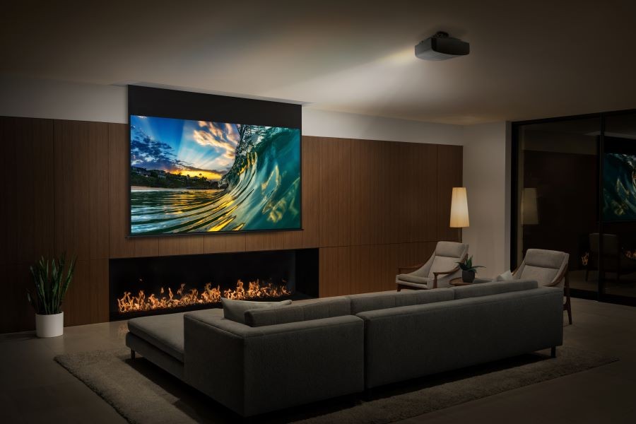A living room with a Sony short-throw projector displaying an image on a screen of a wave breaking.