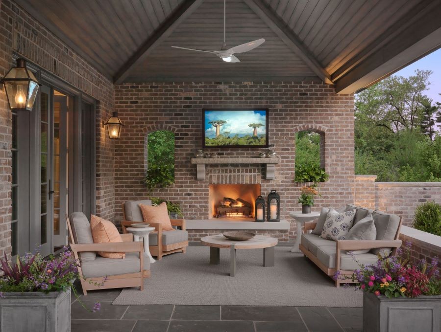 A Séura outdoor TV over a fireplace on a patio with brick walls. 