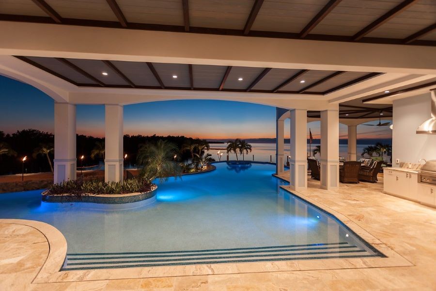 Coastal Source LED tiki torches and niche lights illuminating a pool and ocean-front property.