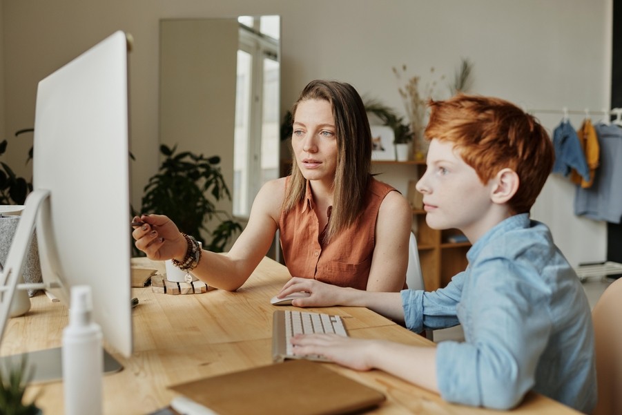 A mother and son sitting at the computer.
