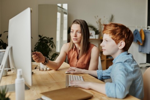 A mother and son sitting at the computer.