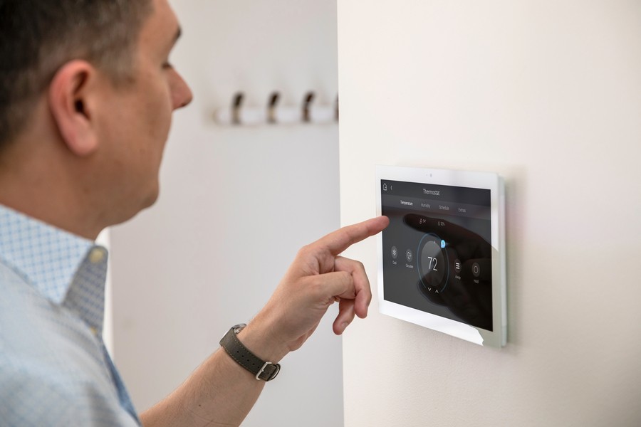 man adjusting the wall-mounted Control4 thermostat.