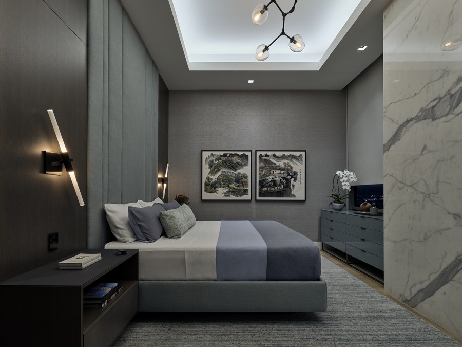 Elegant bedroom with a contemporary design featuring a plush bed, artistic wall sconces, Asian-style artwork, and a marble wall accent.