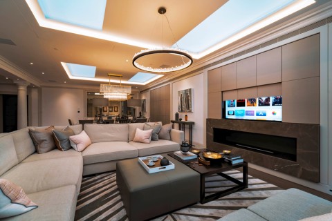 A modern living room with a wall panel rising to reveal a TV.