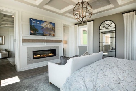 Bedroom with fireplace, a modern spherical hanging light fixture, and a Control4 video display.