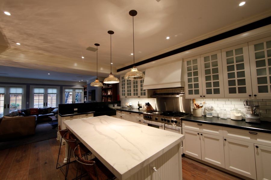 A kitchen well-lit with pendant, recessed, and under cabinet lighting.